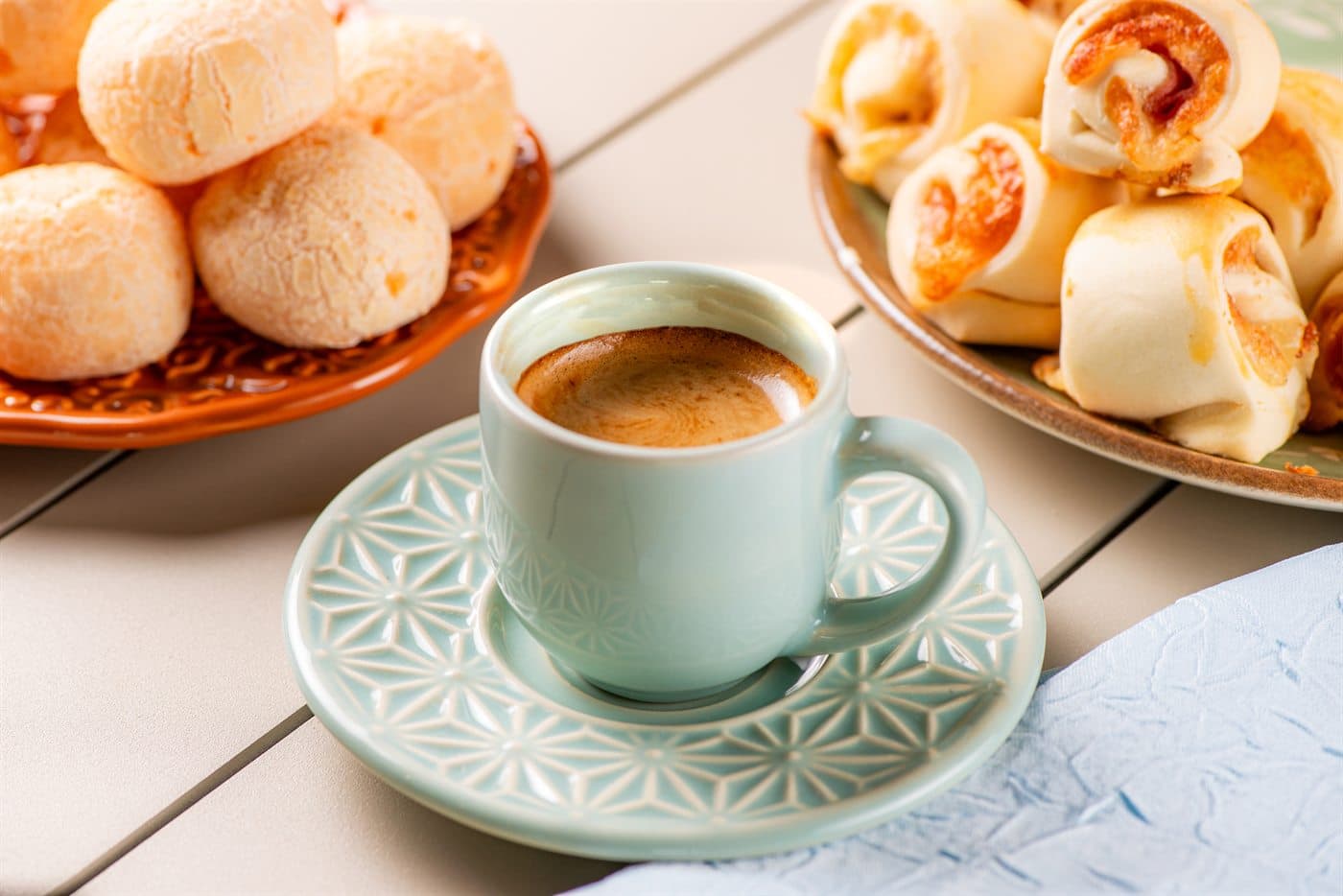 Pão de queijo da Santa Janela em tigela, ao lado de café.