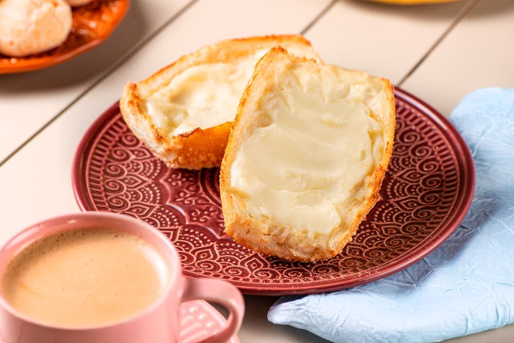 Pão francês na chapa com manteiga e café com leite.