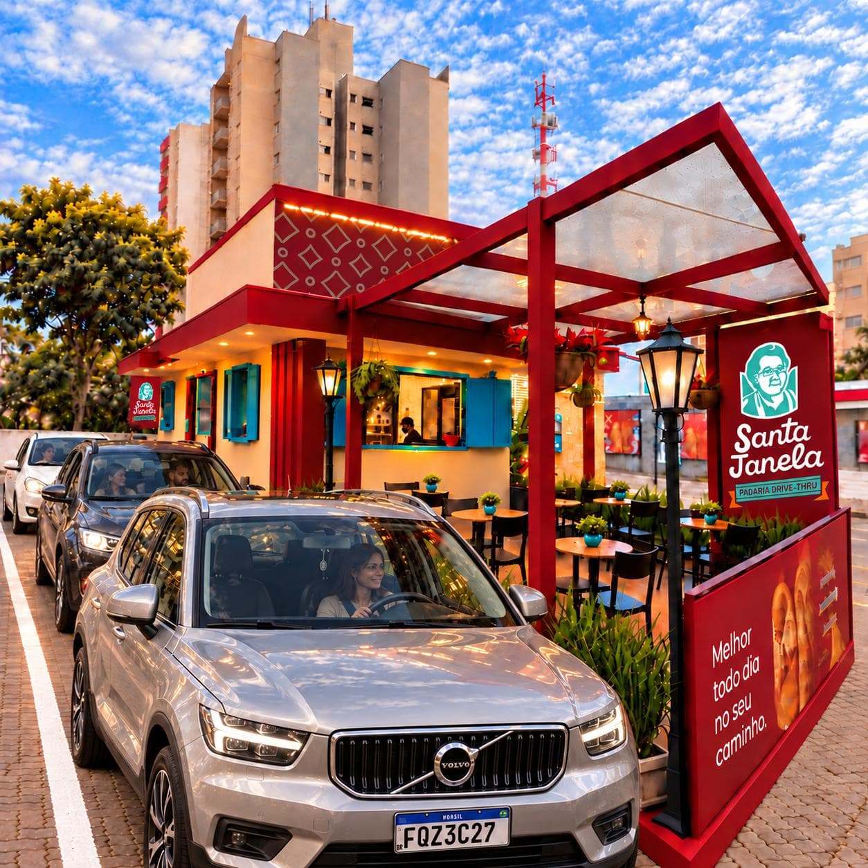 Carros na fila do drive-thru da Santa Janela, ao lado da janela de atendimento com as venezianas azuis abertas e do deque coberto com mesas.